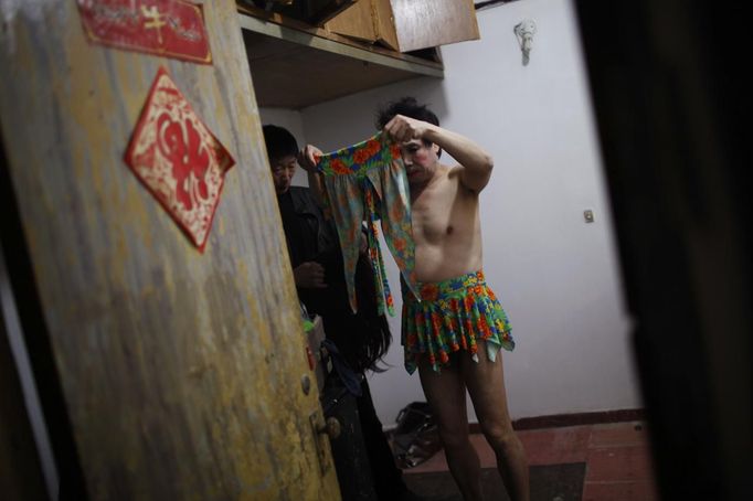 Xiao Cao, a 57-year-old gay man (R), gets dressed in a empty meeting room in Shanghai March 13, 2012. China's gay community has long been on the edges of society but it is gradually becoming more accepted. Cao, who is an unemployed drag queen, is one whose life lifts the curtain on a less romanticised view of Chinese homosexuals. Living in an eight-square-metre apartment behind a public toilet and with a monthly income of 500 yuan ($79) from social insurance, he passes his days dancing in public and spending time with friends at gay clubs. Picture taken March 13, 2012. REUTERS/Aly Song (CHINA - Tags: SOCIETY) CHINA OUT. NO COMMERCIAL OR EDITORIAL SALES IN CHINA. ATTENTION EDITORS PICTURE 08 OF 28 OF PACKAGE 'GAY AND OUT IN CHINA' TO FIND ALL IMAGES SEARCH 'GAY OUT CHINA' Published: Čer. 1, 2012, 12:36 dop.