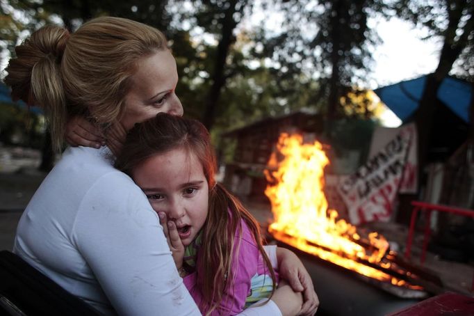 Gema Pardo consoles her daughter Amanda as they sit next to a bonfire with relatives at the Spanish gypsy settlement of Puerta de Hierro outside Madrid October 20, 2011. Fifty-four families have been living in Puerta de Hierro, on the banks of the Manzanares river for over 50 years. Since the summer of 2010, the community has been subject to evictions on the grounds that the dwellings are illegal. Families whose houses have been demolished, move in with relatives whose houses still remain while the debris keeps piling up around them as more demolitions take place. Picture taken October 20, 2011. REUTERS/Susana Vera (SPAIN - Tags: SOCIETY) ATTENTION EDITORS - PICTURE 16 OF 31 FOR PACKAGE 'GYPSY SITE DEMOLISHED' SEARCH 'GYPSY SITE' FOR ALL IMAGES Published: Lis. 5, 2012, 4:11 odp.