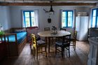 V levé části domu je světnice s dřevěnou podlahou, jídelním dubovým stolem, kachlovými kamny a kuchyní.