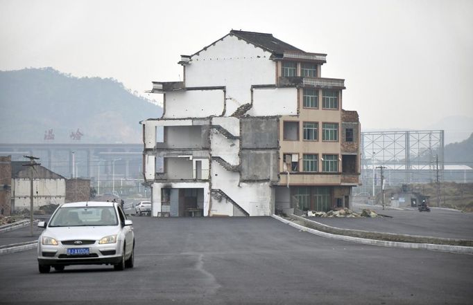 A car drives past a house which stands alone in middle of a newly built road in Wenling, Zhejiang province, November 22, 2012. An elderly couple refused to sign an agreement to allow their house to be demolished. They say that compensation offered is not enough to cover rebuilding costs, according to local media. Their house is the only building left standing on a road which is paved through their village. REUTERS/China Daily (CHINA - Tags: POLITICS SOCIETY) CHINA OUT. NO COMMERCIAL OR EDITORIAL SALES IN CHINA Published: Lis. 22, 2012, 8:36 dop.