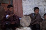 Dva mladí bubeníci v tradičním bhútánském obleku Gho, který musejí nosit všichni studenti i úředníci. Spor tradice a modernosti se někdy projevuje v tom, že muži pod tímto oblekem nosí moderní oblečení.