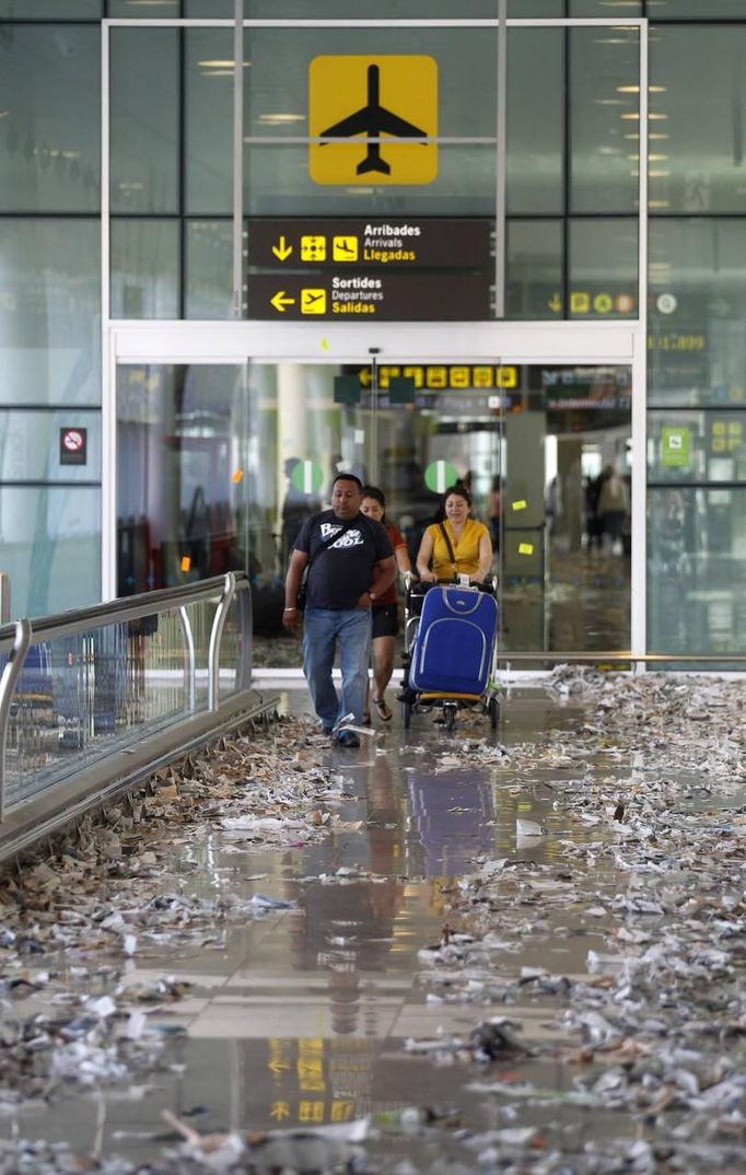 Passengers walk during a protest by the cleaning staff at Barcelona's airport May 29, 2012. Cleaning staff working for a company which has a contract with the airport demonstrated against pay and benefits cuts made by their employer. REUTERS/Albert Gea (SPAIN - Tags: CIVIL UNREST BUSINESS TRANSPORT) Published: Kvě. 29, 2012, 5:12 odp.