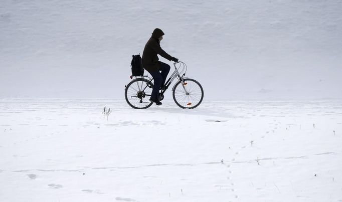 A man rides his bicycle through the snow along the embankment of the river Spree near the governmental district in Berlin, March 12, 2013. REUTERS/Fabrizio Bensch (GERMANY - Tags: ENVIRONMENT) Published: Bře. 12, 2013, 12:28 odp.