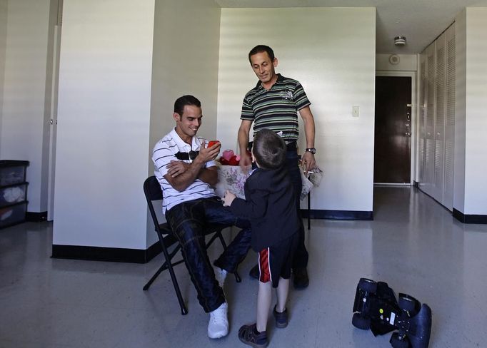 Luis Salgado (L), nicknamed Chucho, spends time with his father, Jesus Salgado (R), and his half brother Kevin, in the apartment of a family friend that is subsidized by the U.S. government for immigrants, a day after Luis arrived from Havana at Miami airport, March 14, 2013. Chucho was granted a U.S. visa based on his father's status as legal resident in Texas, and he was reunited in Miami with his father, who had escaped Cuba on a frail boat ten years earlier. The Salgados are among many Cubans taking advantage of Cuba's new travel policy in place since last January, which allows citizens to leave the country with just a passport and no need for much-hated exit visas required since 1961. Picture taken March 13, 2013. REUTERS/Desmond Boylan (UNITED STATES - Tags: POLITICS SOCIETY) Published: Dub. 11, 2013, 1:46 odp.