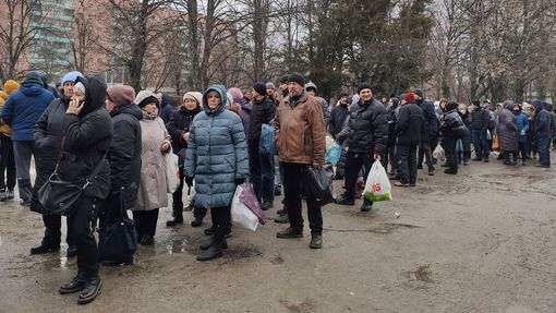 Obyvatelé ostřelovaného Charkova stojí frontu před místní nemocnicí, která distribuuje jídlo.