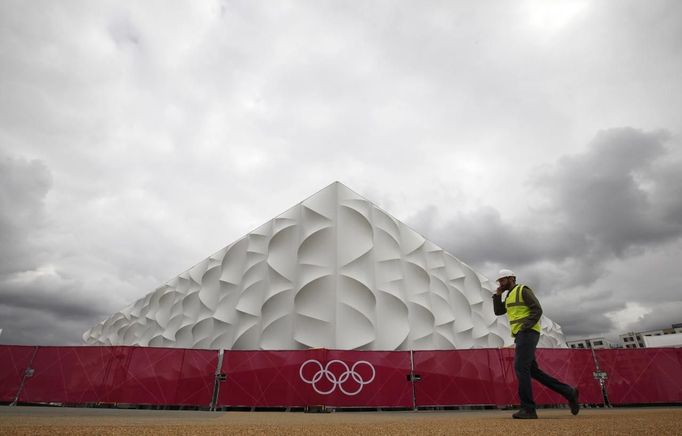 A worker walks past the Olympic basketball arena in Olympic Park, Stratford, east London, July 19, 2012. The 2012 London Olympic Games will begin in just over a week. REUTERS/Andrew Winning (BRITAIN - Tags: SPORT OLYMPICS BASKETBALL) Published: Čec. 19, 2012, 1:31 odp.