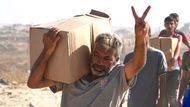 Palestinský muž v Rafáhu a jeho vítězné gesto při převzetí balíku s potravinami a další pomocí od Gaza Humanitarian Foundation.