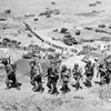 Handout photo of U.S. Army reinforcements marching up a hill past a German bunker after the D-Day landings near Colleville sur Mer
