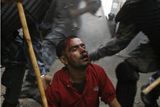 Nepálská policie bije zraněného demonstranta v Gongabhu v Káthmándú. Tisíce rozzlobených Nepálců se v neděli snažilo dostat se do státní nemocnice a pálili vládní vozidla. Střety s policií propukly i přes vyhlášení zákazu vycházení.