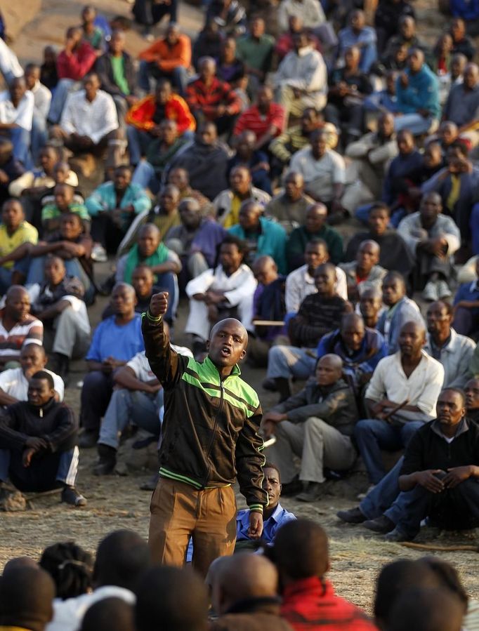 The leader of striking miners (C) addresses his colleagues as they gather outside a South African mine in Rustenburg, 100 km (62 miles) northwest of Johannesburg, August 15, 2012. Thousands of striking miners armed with machetes and sticks faced off with South African police on Wednesday at Lonmin's Marikana mine after it halted production following the deaths of 10 people in fighting between rival unions. Lonmin, the world's third-largest platinum producer, has threatened to sack 3,000 rock drill operators if they fail to end a wildcat pay strike that started on Friday at its flagship mine Marikana. REUTERS/Siphiwe Sibeko (SOUTH AFRICA - Tags: CIVIL UNREST BUSINESS EMPLOYMENT) Published: Srp. 15, 2012, 4:37 odp.