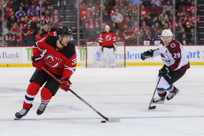 Jan 4, 2020; Newark, New Jersey, USA; New Jersey Devils center Pavel Zacha (37) skates with the puck past Colorado Avalanche center Nathan MacKinnon (29) during the secon