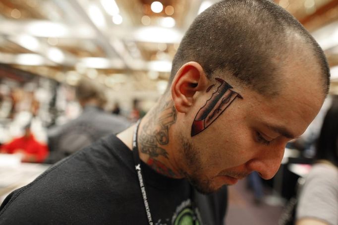 A client shows his new knife tattoo, which appears on both sides of his face, at the National Tattoo Association Convention in Cincinnati, Ohio April 14, 2012. The hobby of collecting tattoos has exploded into the mainstream of society with tattoo conventions and festivals held year-round across the United States and the world. Picture taken April 14, 2012. REUTERS/Larry Downing (UNITED STATES - Tags: SOCIETY) ATTENTION EDITORS PICTURE 12 OF 31 FOR PACKAGE 'ADDICTED TO THE NEEDLE' TO FIND ALL PICTURES SEARCH 'ADDICTED NEEDLE' Published: Čer. 29, 2012, 12:59 odp.