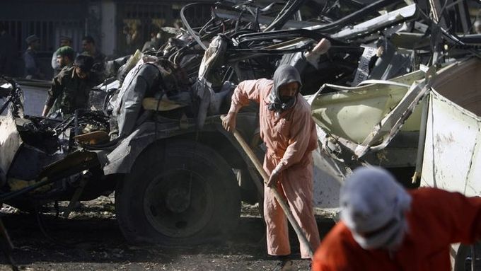 Záchranář odklízí trosky autobusu, který v dopravní špičce explodoval v ulicích Kábulu