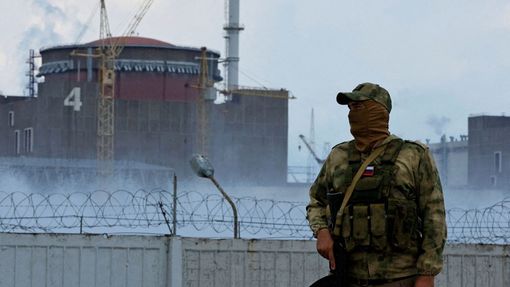Ruský voják hlídkuje před Záporožskou jadernou elektrárnou. Ruská armáda ji obsadila na začátku března.