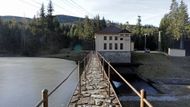 Budova elektrárny Černé jezero. Pohled z gravitační hráze s délkou v koruně 64,10 metru, výškou nad terénem 7 metrů a celkovou výškou včetně základů 15,6 metru. Zásoba vody ve spodní nádrži umožňuje čerpat až 10 hodin denně. Vyrábět elektřinu z přečerpané vody lze až 5 hodin denně.