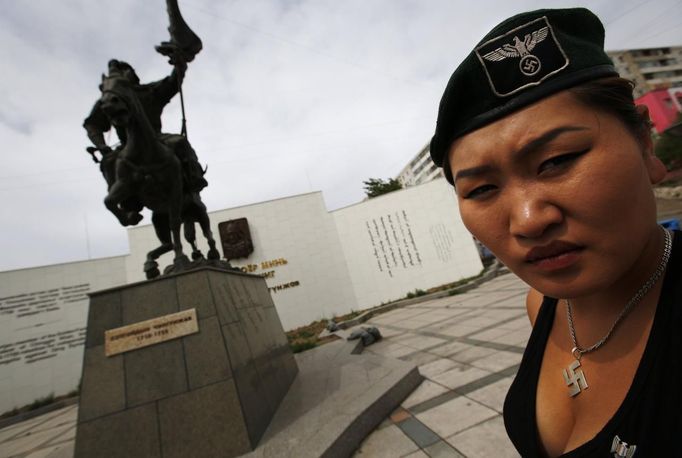 Uranjargal, a leader of the Mongolian neo-Nazi group Tsagaan Khass, stands next to a statue of Chingunjav, a Mongolian national hero, in Ulan Bator June 22, 2013. The group has rebranded itself as an environmentalist organisation fighting pollution by foreign-owned mines, seeking legitimacy as it sends Swastika-wearing members to check mining permits. Over the past years, ultra-nationalist groups have expanded in the country and among those garnering attention is Tsagaan Khass, which has recently shifted its focus from activities such as attacks on women it accuses of consorting with foreign men to environmental issues, with the stated goal of protecting Mongolia from foreign mining interests. This ultra-nationalist group was founded in the 1990s and currently has 100-plus members. Picture taken June 22, 2013. REUTERS/Carlos Barria (MONGOLIA - Tags: SOCIETY POLITICS) ATTENTION EDITORS: PICTURE 10 OF 25 FOR PACKAGE 'MONGOLIA'S ENVIRONMENTAL NEO-NAZIS'. TO FIND ALL IMAGES SEARCH 'TSAGAAN KHASS' Published: Čec. 2, 2013, 9:58 dop.