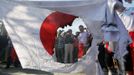 Protesters laugh and take pictures next to a burned Japanese national flag during an anti-Japan protest in Wuhan, Hubei province September 16, 2012. Angry anti-Japan protesters took to the streets of Chinese cities for a second day on Sunday, with Japan's prime minister urging Beijing to protect his country's companies and diplomatic buildings from fresh assaults over a territorial dispute. REUTERS/Stringer (CHINA - Tags: CIVIL UNREST POLITICS TPX IMAGES OF THE DAY) CHINA OUT. NO COMMERCIAL OR EDITORIAL SALES IN CHINA