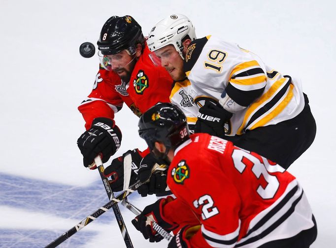 Boston Bruins' Tyler Seguin (19) battles for the puck with Chicago Blackhawks' Nick Leddy (8) and Michal Rozsival (32) during the first period in Game 1 of their NHL Stan