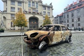 Za čtyřmi ohořelými nebo rozstřílenými vraky aut na náměstí jsou čtyři příběhy