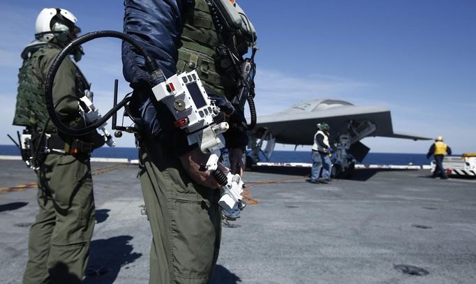 Northrop Grumman test pilots Bruce McFadden (L) and Dave Lorenz are pictured with their arm-mounted controllers in front of an an X-47B pilot-less drone combat aircraft b