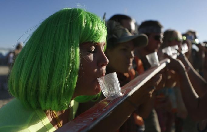 A woman of the playa name "Indigo" participates in a drinking game during the Burning Man 2012 "Fertility 2.0" arts and music festival in the Black Rock Desert of Nevada August 29, 2012. More than 60,000 people from all over the world have gathered at the sold out festival, which is celebrating its 26th year, to spend a week in the remote desert cut off from much of the outside world to experience art, music and the unique community that develops.