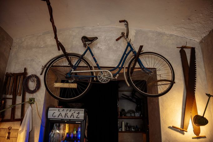 Kávu připravuje za barem, nad kterým visí kolo značky, na němž jeli Gabčík a Kubiš během atentátu na Heydricha.