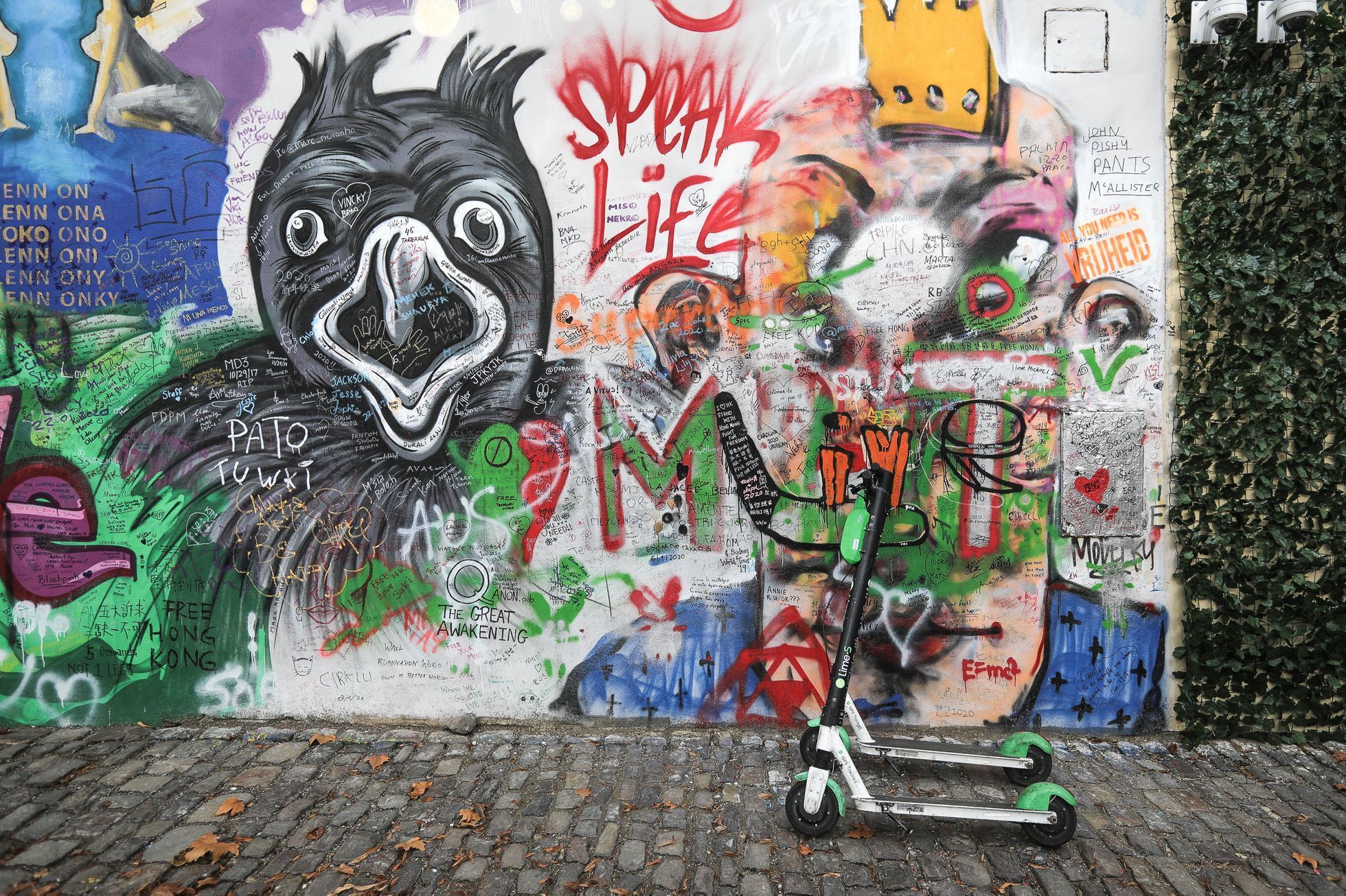Lennonova zeď po třech měsících od malování - turisté, graffiti