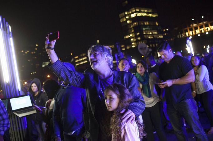 People watch as magician David Blaine channels bolts of electricity from various tesla coils charged with one million volts of electricity during a stunt on Pier 54 in New York, October 5, 2012. Blaine hopes to stand in the same position for 72 hours. REUTERS/Andrew Burton (UNITED STATES - Tags: SOCIETY ENTERTAINMENT) Published: Říj. 6, 2012, 4:06 dop.