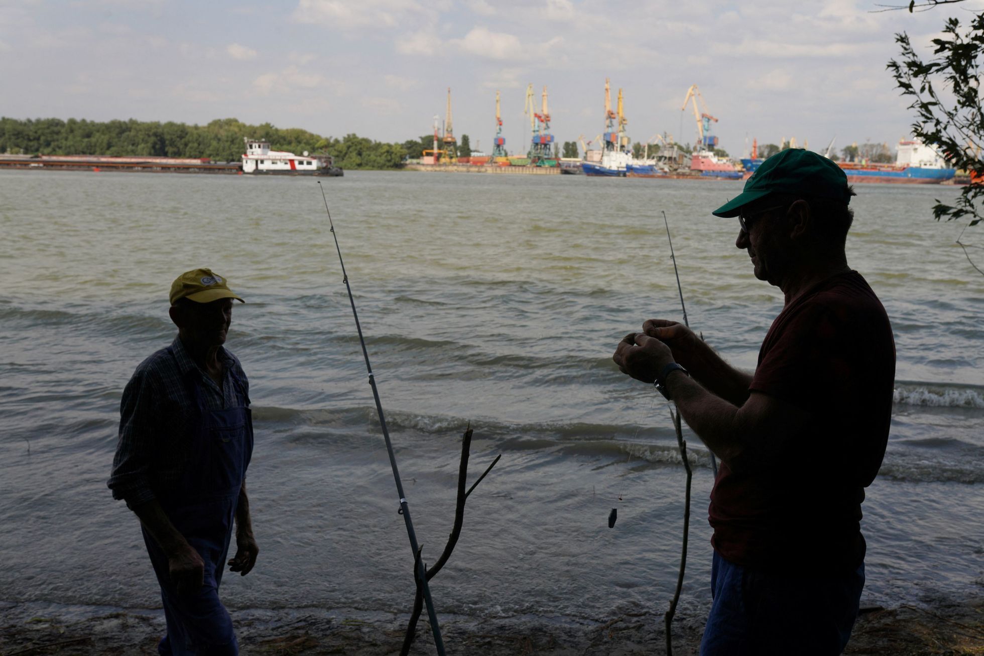 Rybáři ve městě Plauru, na rumunské straně Dunaje. Na opačném břehu je vidět ukrajinský přístav Izmajil, na který Rusové útočí.