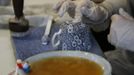 A worker applies tissue paper transfers to a cup in a workshop at the Middleport pottery in Stoke-on-Trent, central England January 22, 2013. The pottery which dates back to 1888 and was rescued from closure in 2009, continues to use traditional methods to produce its range of ceramics and famous Burleigh Ware pottery. REUTERS/Phil Noble (BRITAIN - Tags: BUSINESS EMPLOYMENT SOCIETY) Published: Led. 22, 2013, 4:40 odp.