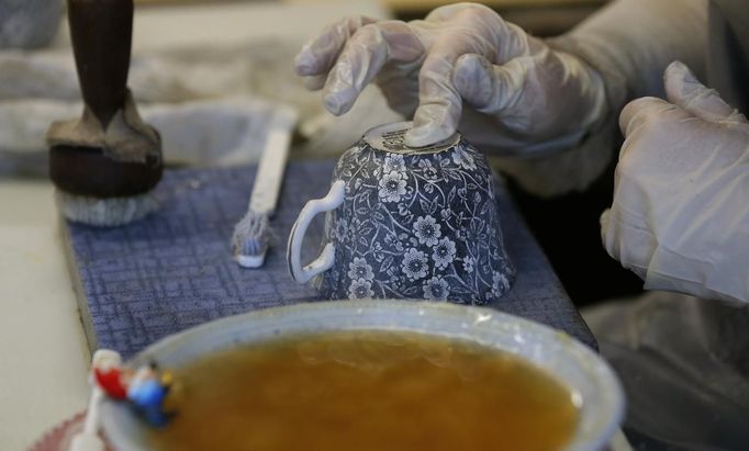 A worker applies tissue paper transfers to a cup in a workshop at the Middleport pottery in Stoke-on-Trent, central England January 22, 2013. The pottery which dates back to 1888 and was rescued from closure in 2009, continues to use traditional methods to produce its range of ceramics and famous Burleigh Ware pottery. REUTERS/Phil Noble (BRITAIN - Tags: BUSINESS EMPLOYMENT SOCIETY) Published: Led. 22, 2013, 4:40 odp.