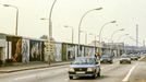 Berlínská zeď s malbami podél Mühlenstrasse, známá jako East Side Gallery, s projíždějícími automobily. Rok 1990