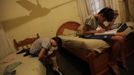 Gabriel Muniz, 11, puts on his prosthesis as his brother Mateus studies at home in Campos dos Goytacazes, 274 kilometres (170 miles) northeast of Rio de Janeiro August 23, 2012. Despite being born with malformation of his feet, fourth grader Gabriel puts in hours into soccer everyday in his neighbourhood. He aspires to be a professional soccer player just like his idol Argentina's Lionel Messi of Barcelona FC. REUTERS/Ricardo Moraes (BRAZIL - Tags: SPORT SOCCER SOCIETY HEALTH TPX IMAGES OF THE DAY) Published: Srp. 24, 2012, 2:25 dop.