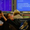 Passengers sit near information boards as they wait for their flights at Fraport airport in Frankfurt