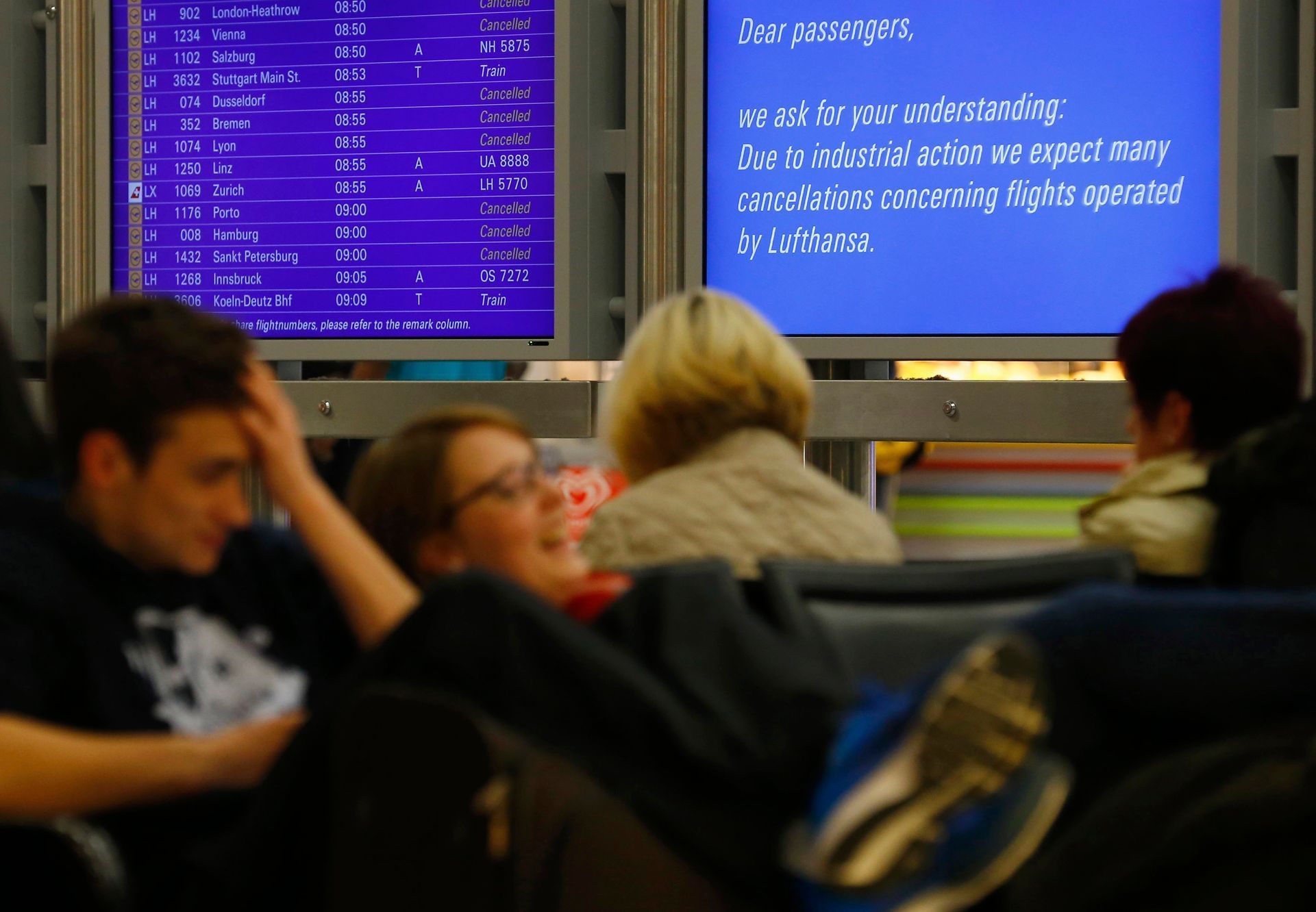 Passengers sit near information boards as they wait for their flights at Fraport airport in Frankfurt