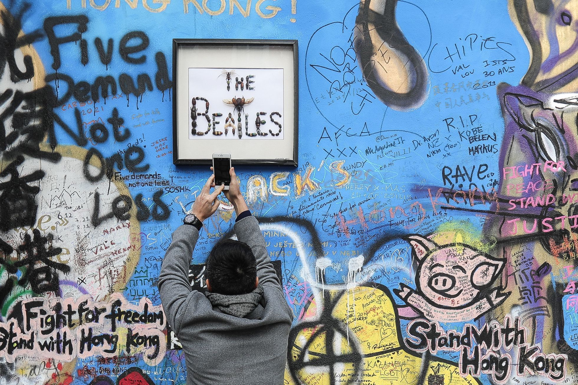 Lennonova zeď po třech měsících od malování - turisté, graffiti