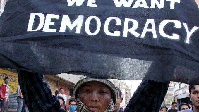 Demonstrant v Nepálu drží transparent s nápisem "Chceme demokracii"