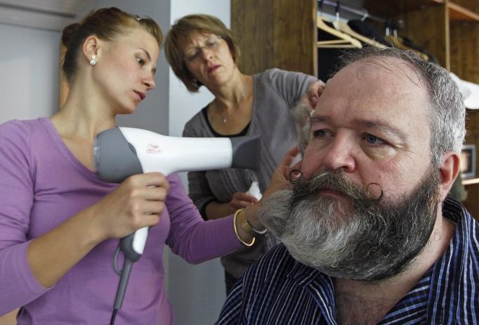 German hairdresser Elmar Weisser (R), 48, is helped by his wife Monica (C) and his friend Jessica as they start shaping his beard as a stork to compete in the 2012 European Beard and Moustache Championships in Wittersdorf near Mulhouse, Eastern France, September 22, 2012. Weisser, who won the World Beard and Moustache Championship in 2011, ranked second in the freestyle category of the European championships on Saturday. Picture taken September 22, 2012. REUTERS/Vincent Kessler (FRANCE - Tags: SOCIETY) Published: Zář. 23, 2012, 11:49 dop.