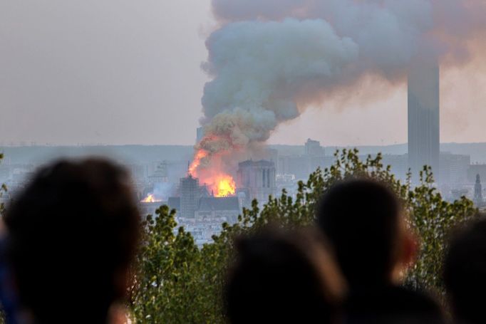 Notre-Dame v Paříži hoří, pohled z Montmartru, pondělí 15. dubna 2019. Hustý kouř stoupá nad katedrálou, zatímco popel padá na turisty na ostrově