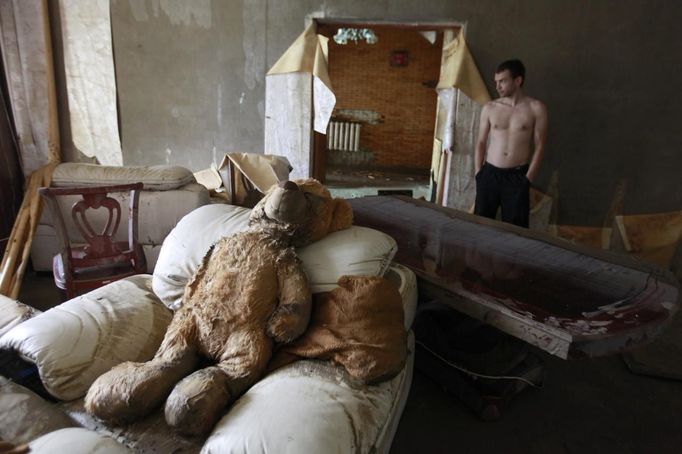 A man stands inside a house damaged by floods in the town of Krymsk in the Krasnodar region, southern Russia, July 8, 2012. in Russian President Vladimir Putin ordered investigators to find out if enough was done to prevent 144 people being killed in floods in southern Russia after flying to the region to deal with the first big disaster of his new presidency. REUTERS/Eduard Korniyenko (RUSSIA - Tags: DISASTER ENVIRONMENT POLITICS) Published: Čec. 8, 2012, 11:47 dop.