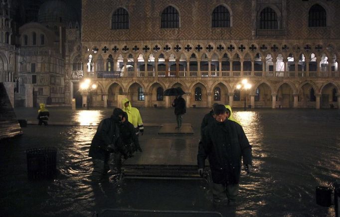 Workers set up platforms for flood waters in a flooded St Mark's Square at night during a period of seasonal high water in Venice November 1, 2012. The water level in the canal city rose to 140 cm (55 inches) above normal, according to the monitoring institute. REUTERS/Manuel Silvestri (ITALY - Tags: ENVIRONMENT SOCIETY TRAVEL DISASTER) Published: Lis. 1, 2012, 8:10 dop.