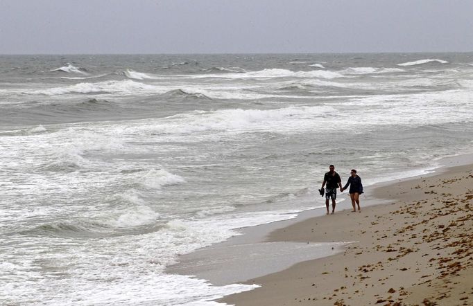 A couple walks on the beach after lifeguards closed the area for swimming as winds from Hurricane Sandy begin to affect weather in Deerfield Beach, Florida October 25, 2012. REUTERS/Joe Skipper (UNITED STATES - Tags: ENVIRONMENT) Published: Říj. 25, 2012, 4:36 odp.