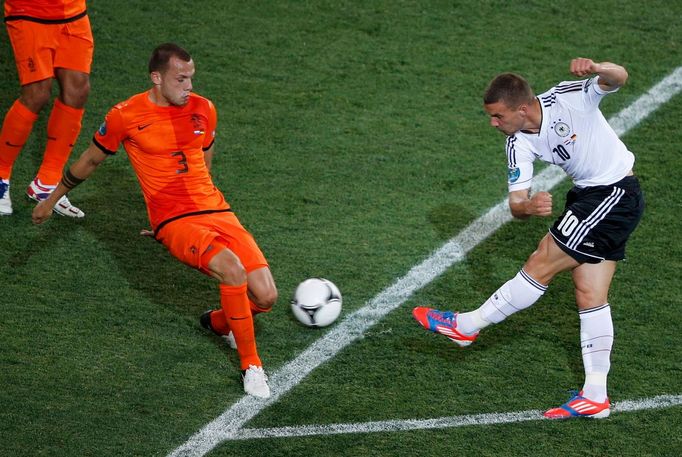 Lukas Podolski se snaží pálit přes Johna Heitingu během utkání Nizozemska s Německem ve skupině B na Euru 2012.