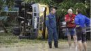 An emergency service worker (L) stands near an overturned car in the southern Russian town of Krymsk July 7, 2012. At least 99 people were killed in floods and landslides in southern Russia after two months' average rainfall fell in a few hours overnight, police and emergency officials said on Saturday. REUTERS/Vladimir Anosov (RUSSIA - Tags: DISASTER ENVIRONMENT) Published: Čec. 7, 2012, 3:37 odp.