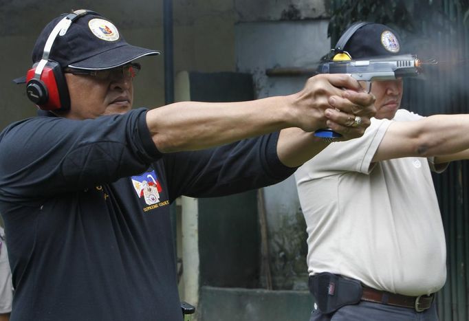 Jaime 'Jimmy' Santiago (L) with his fellow court Judge Emilio Legazpi III fire service pistols during shooting practice with fellow court Judges at a police firing range in Manila March 6, 2013. Jaime 'Jimmy' Santiago, a former police officer who headed a special weapons and tactics (SWAT) unit, now a lower court judges in Manila, favours arming Filipino judges to protect themselves from disgruntled litigants who can't accept decisions and criminal syndicates whose members were sent to jail. There had been cases of shootings inside courtrooms. REUTERS/Romeo Ranoco (PHILIPPINES - Tags: POLITICS CRIME LAW) Published: Dub. 4, 2013, 11:18 dop.