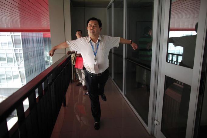 A trainee stretches during a break as he attends a training course at the communist party school called China Executive Leadership Academy of Pudong in Shanghai, September 24, 2012. China's Communist Party has dramatically stepped up its training of the country's roughly 40 million party and government officials in the past decade. With public scrutiny of cadre behaviour growing via social media, the party is likely to call for continued, and deepened, cadre education at the upcoming 18th Party Congress. At the vanguard of this education drive, alongside a Central Party School in Beijing, are three "Executive Leadership Academies" which opened in 2005 for middle-ranking and senior officials in Shanghai, Yan'an and Jinggangshan. The curriculum covers Marxism, Leninism and Mao Zedong Thought, but students may also take finance courses, receive in-depth media training or role-play crisis management scenarios on everything from disease outbreaks to train wrecks. REUTERS/Carlos Barria (CHINA - Tags: POLITICS SOCIETY) Published: Zář. 24, 2012, 2:19 odp.