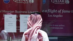 Muž si pročítá nápis na dveřích Qatar Airways.