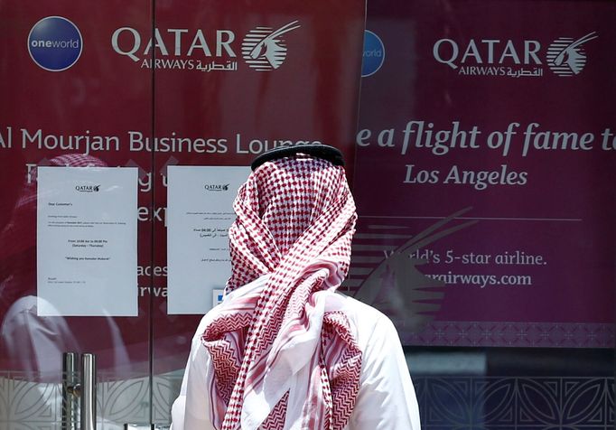 Muž si pročítá nápis na dveřích Qatar Airways.