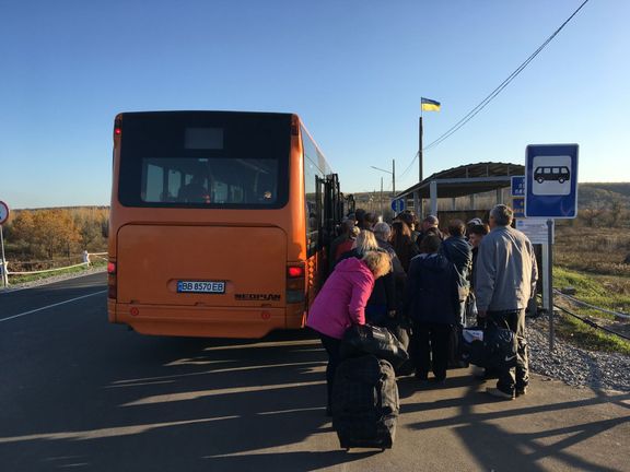 Lidé nastupují do autobusu, který je převeze přes most na území pod kontrolou separatistů.