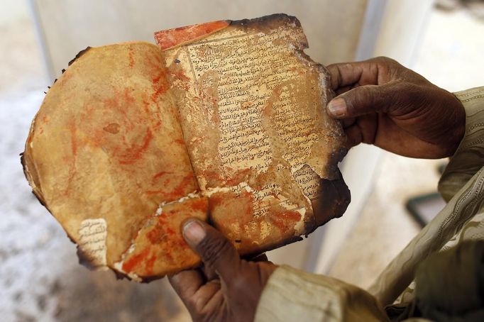 A museum guard displays a burnt ancient manuscript at the Ahmed Baba Institute, or Ahmed Baba Centre for Documentation and Research, in Timbuktu January 31, 2013. The majority of Timbuktu's ancient manuscripts appear to be safe and undamaged after the Saharan city's 10-month occupation by Islamist rebel fighters, experts said on Wednesday, rejecting some media reports of their widespread destruction. REUTERS/Benoit Tessier (MALI - Tags: POLITICS CIVIL UNREST CONFLICT SOCIETY TPX IMAGES OF THE DAY) Published: Led. 31, 2013, 6:53 odp.